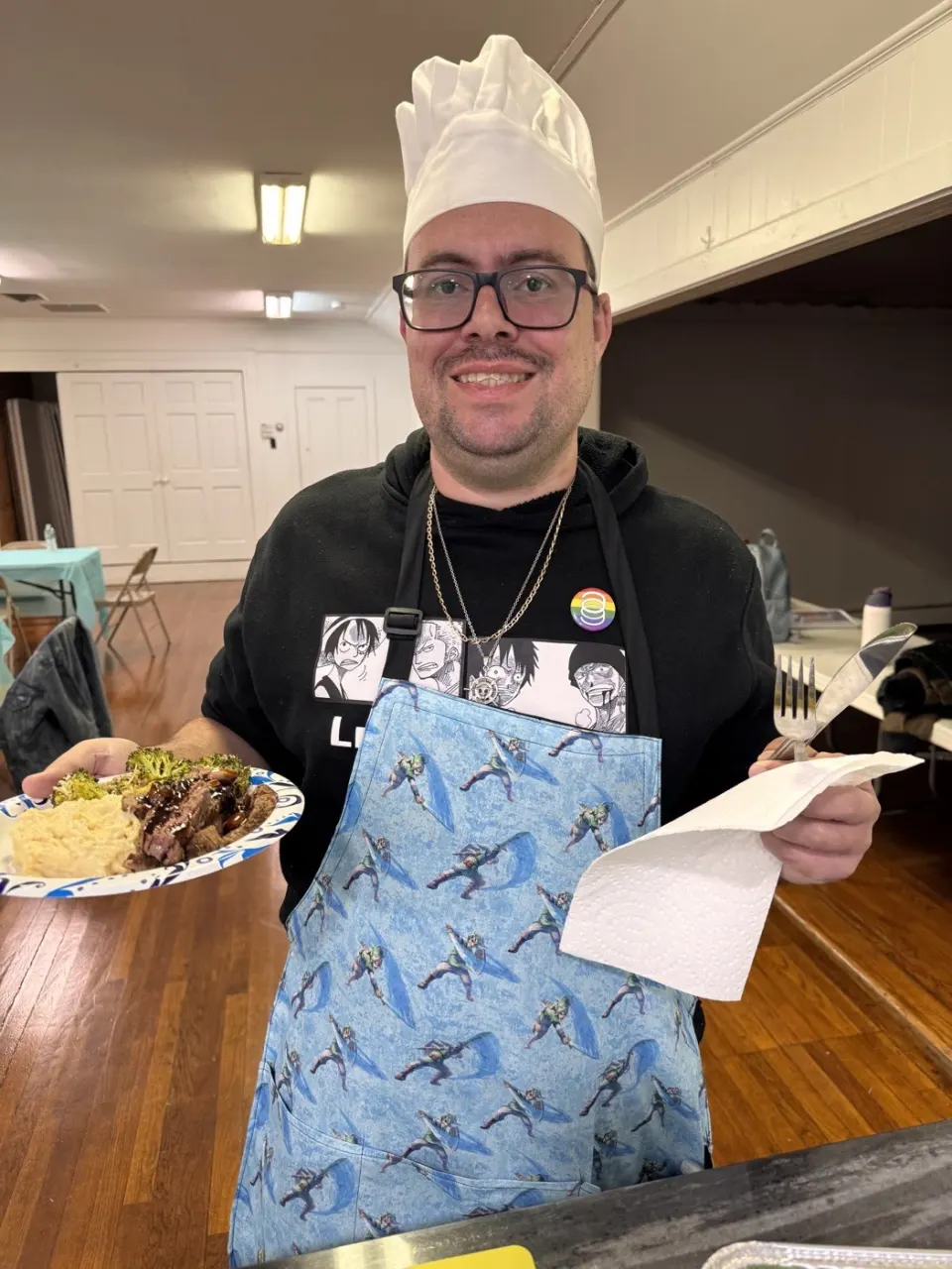 Move Academia cooking workshop member in a chef's hat with their plated meal